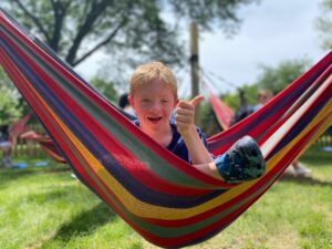 Camper sitting in a hammock with his thumbs up