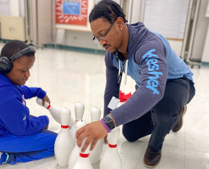 Deiondre helping a student set up bowling pins