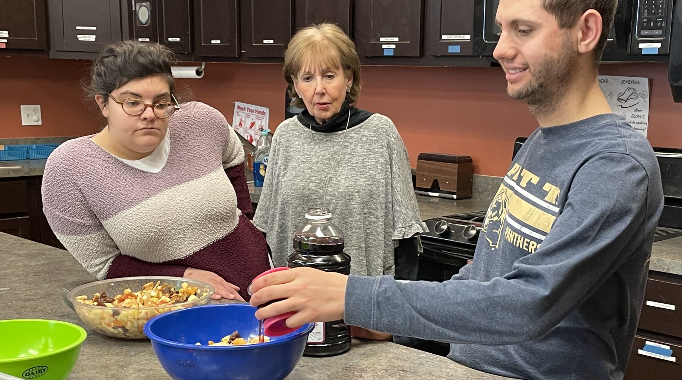 Team member and staff mixing and pouring into the charoset recipe