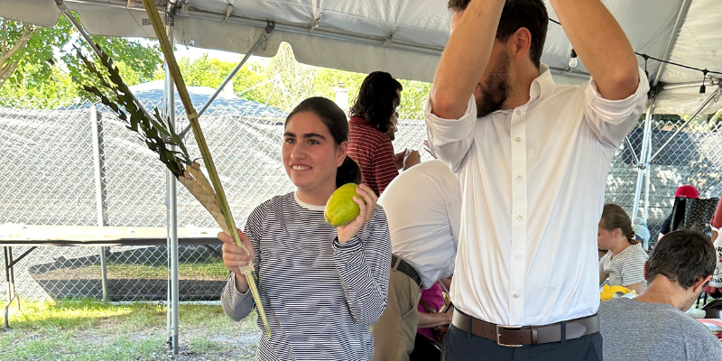 Transition student shaking the lulav and etrog with the rabbi