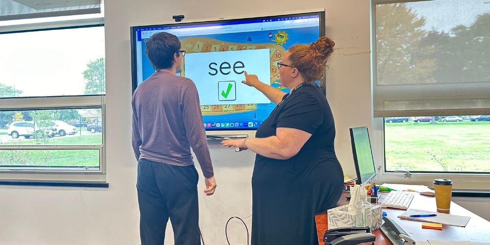 Student and teacher working on an activity using a smartboard in the classroom