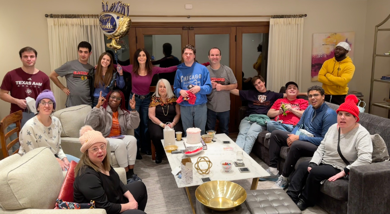 MY Life residents, staff and Fishman family sitting in the family room at the Fishman house hanukkah party