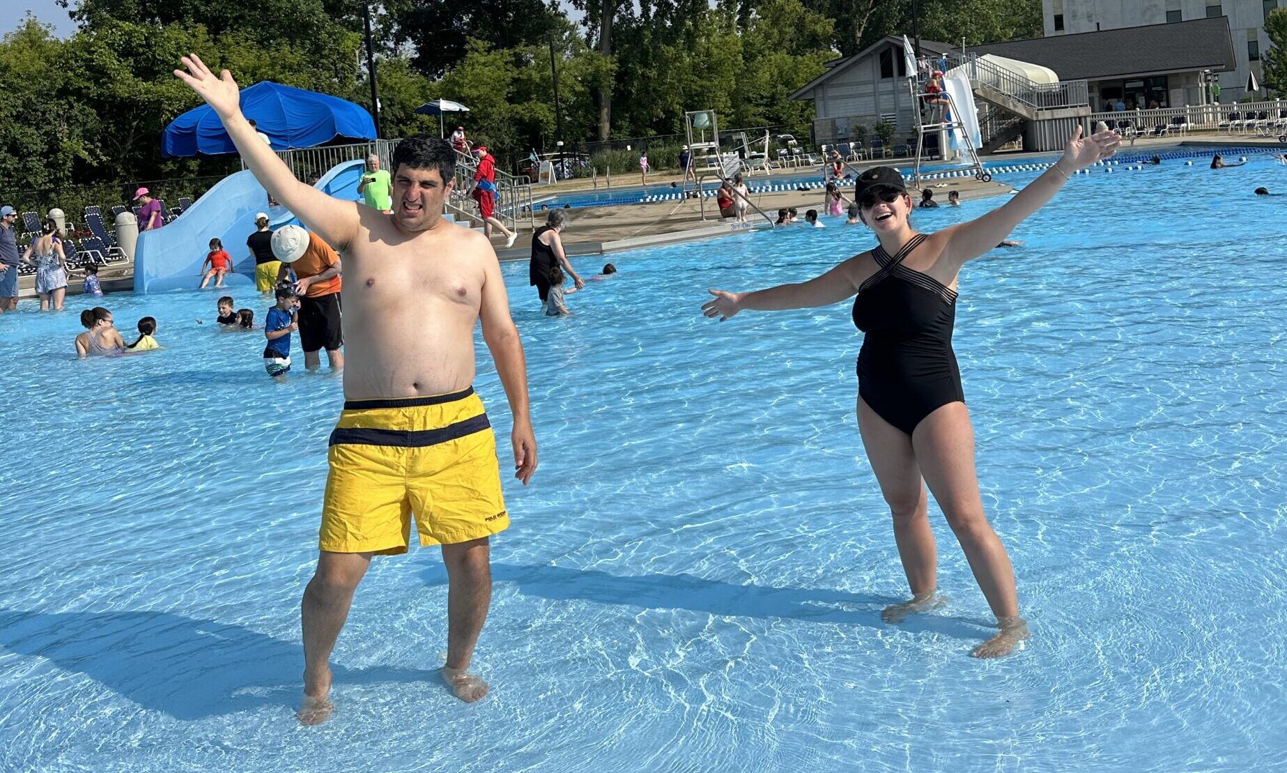 Adult participant and staff in the water with their hands up in the air