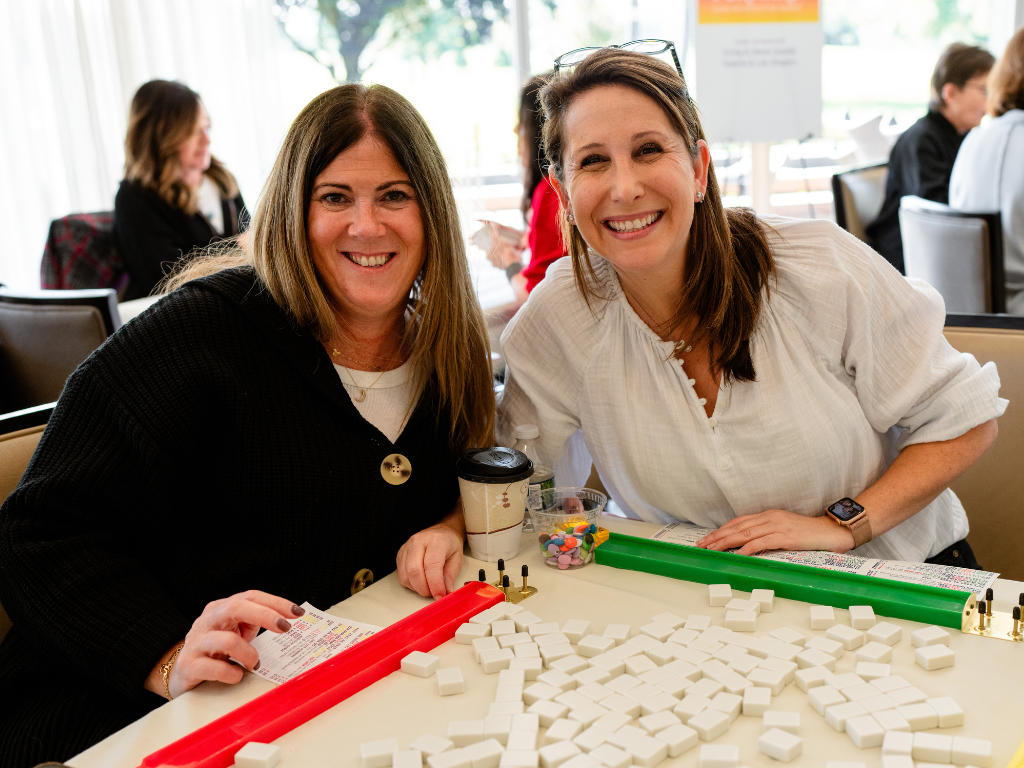 Two women smiling with their mahjong sets at last year's play it forward