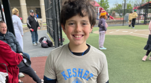 Charlie smiling in his Keshet sports t-shirt at baseball