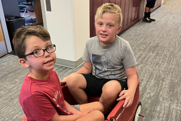 Two young boys sitting in a wagon and smiling