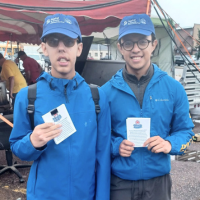 Two men wearing Habitat for Humanity hats and shirts voluntering at an event