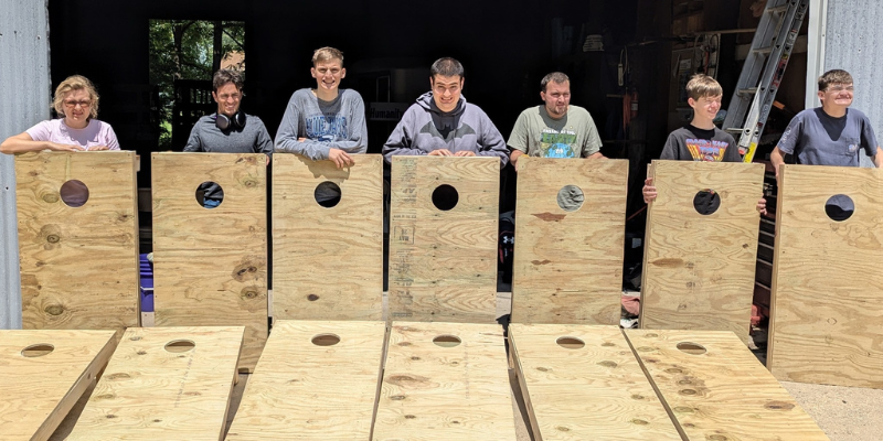 Group posing in front of the unpainted corn holes they built.