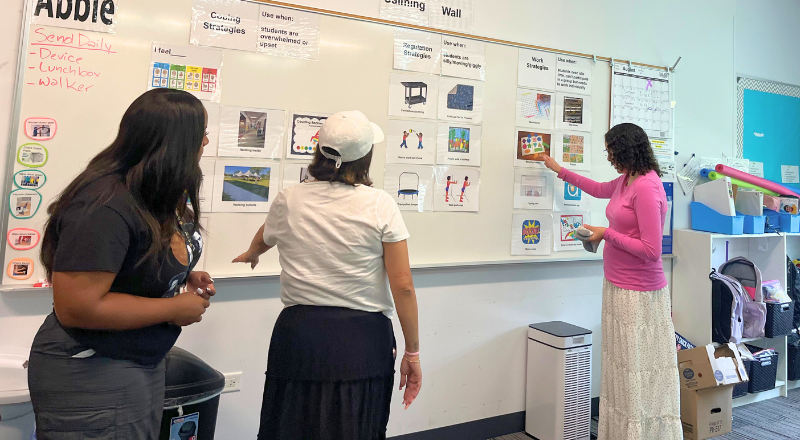 Students and staff working together to place pictures on a white board