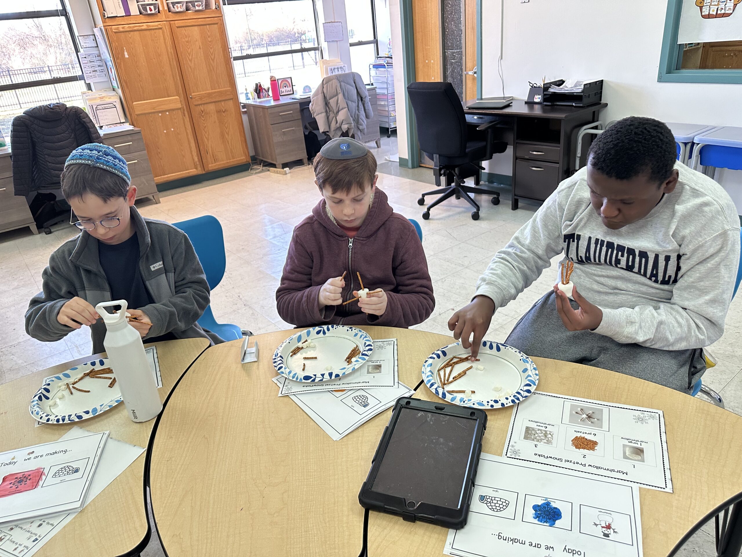 Three students making candy dreidels