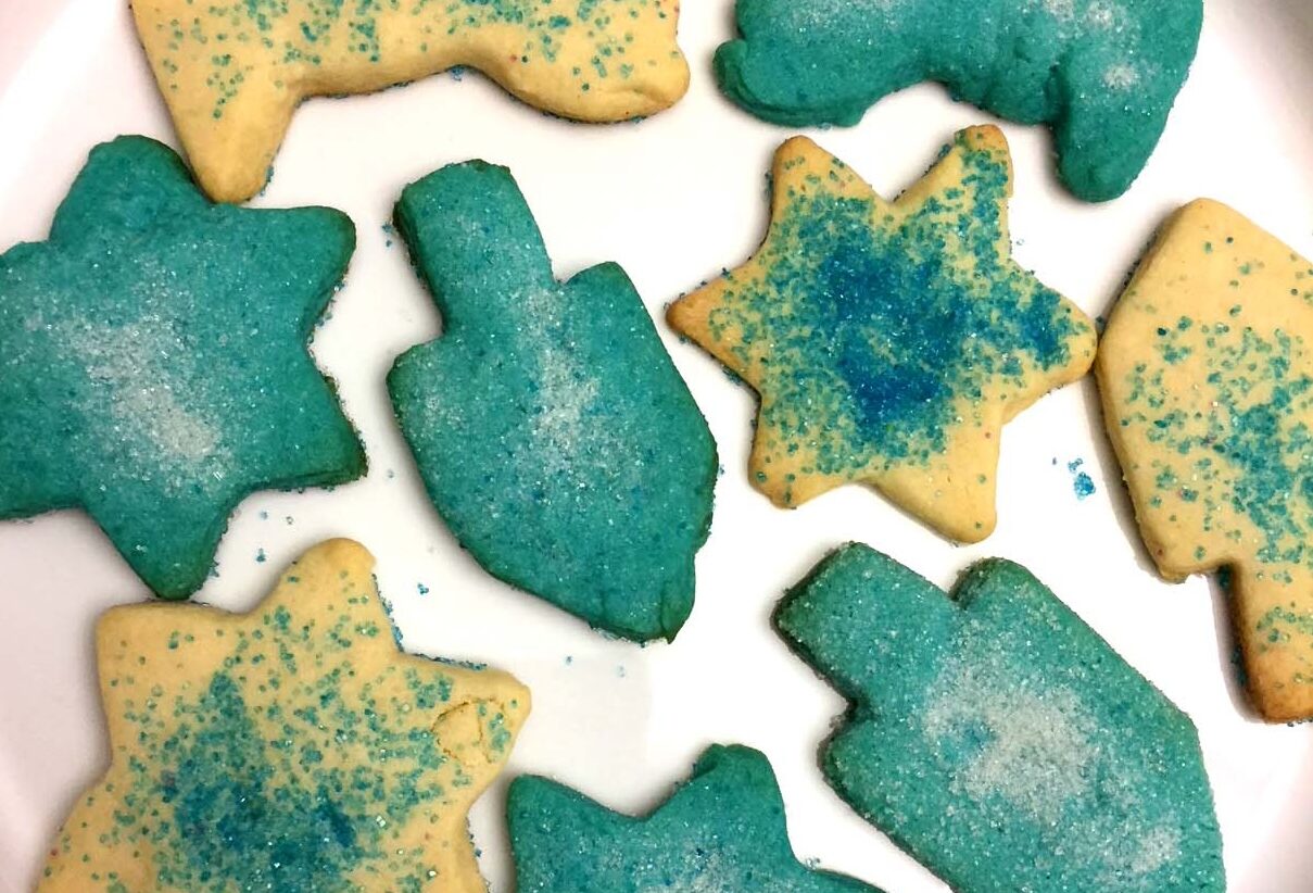 Dreidel and Jewish star shaped sugar cookies topped with blue sprinkles