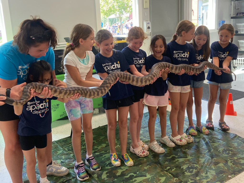 Group of campers in Apachi t-shirt and holding a long snake