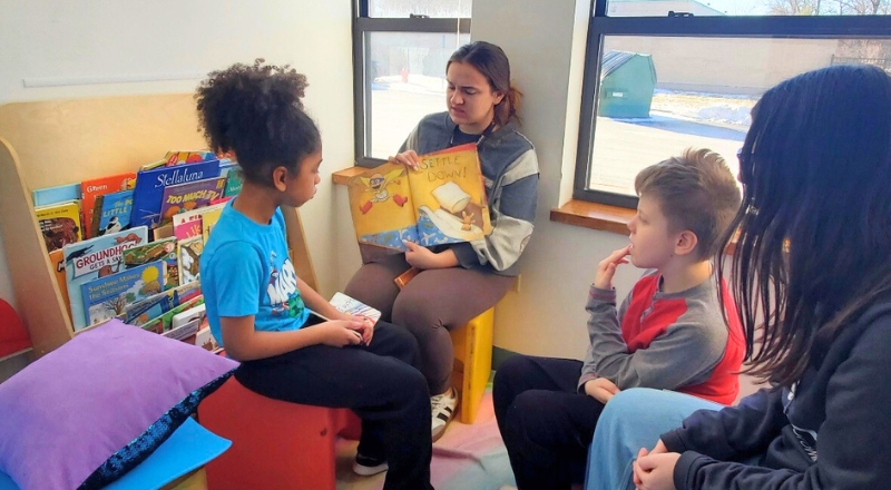 Jessica reading a picture book to two students