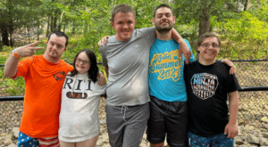 Five campers standing in front of trees with their arms around each other