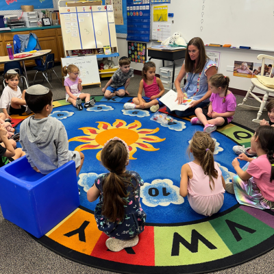 Group of students sitting around a letter rug