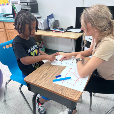 Student and staff sitting at a desk working on a worksheet