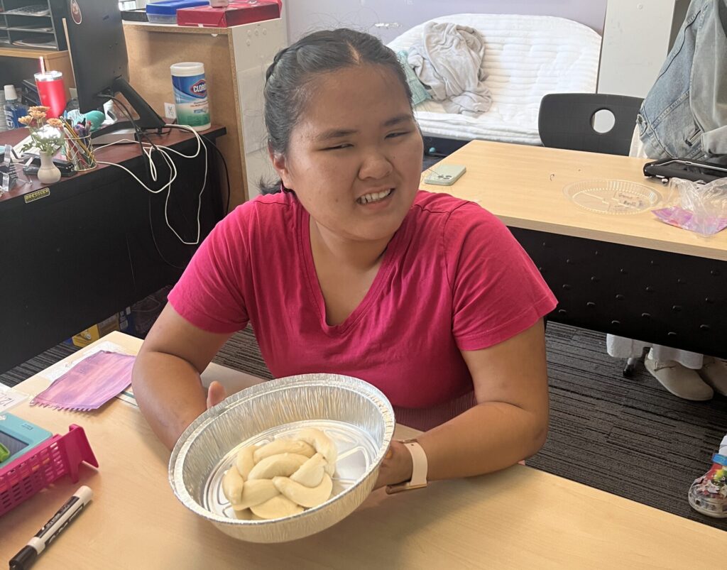 Student smiling holding a round challah
