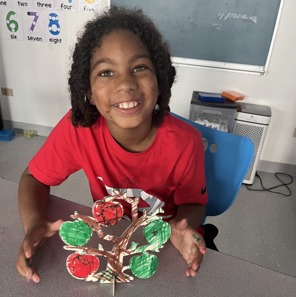 Student smiling with an apple tree art project