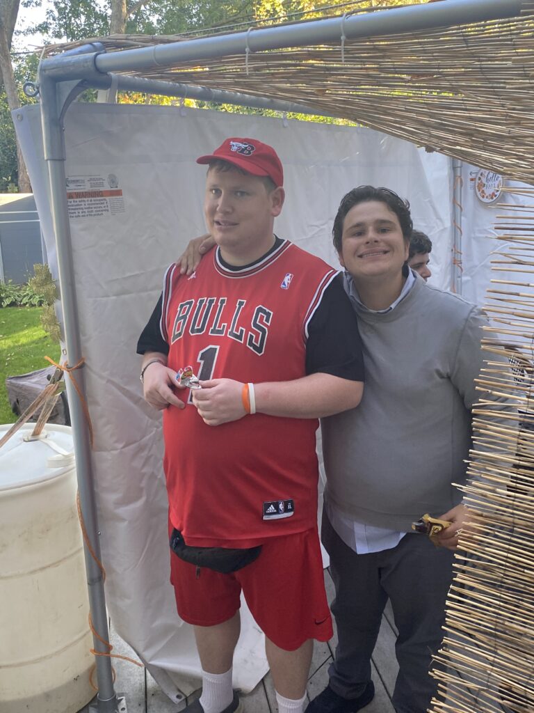 Two residents standing inside a sukkah