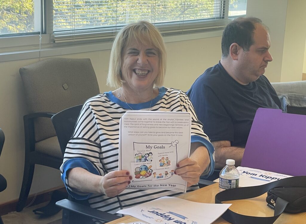 Adult smiling while holding up a sheet that says "my goals"