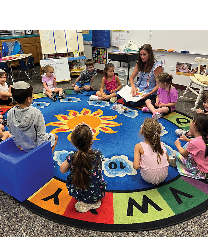 Students sitting around a rug with their teacher