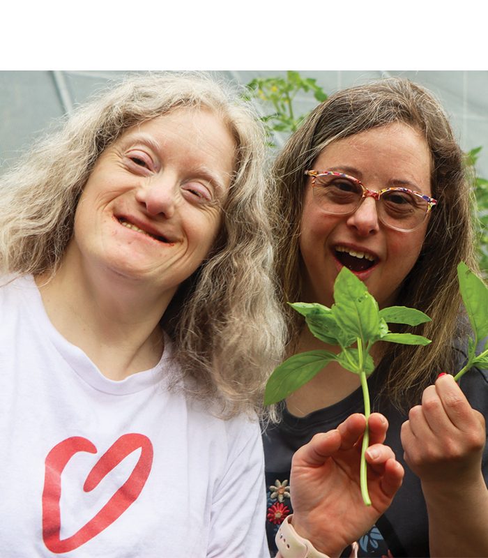 Two adults smiling and holding herbs