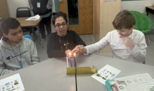 Batel lighting the menorah with students