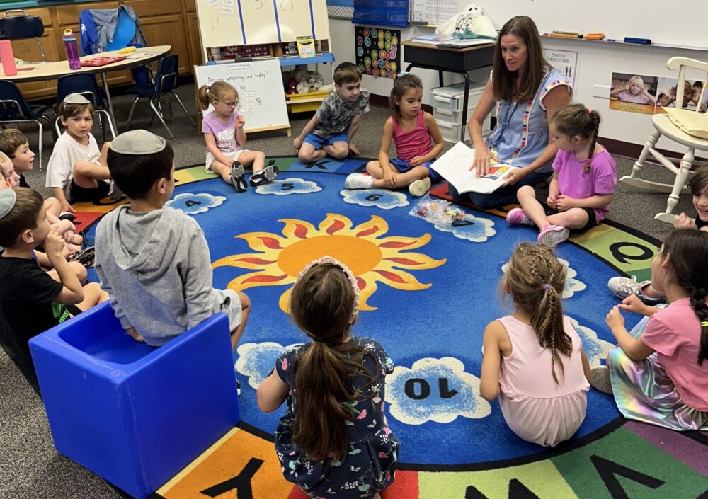 Students sitting around a rug with their teacher