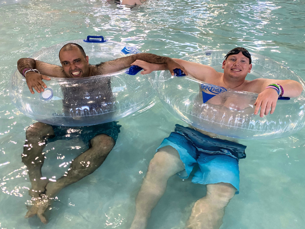 two adults smiling in a pool inside inner tubes