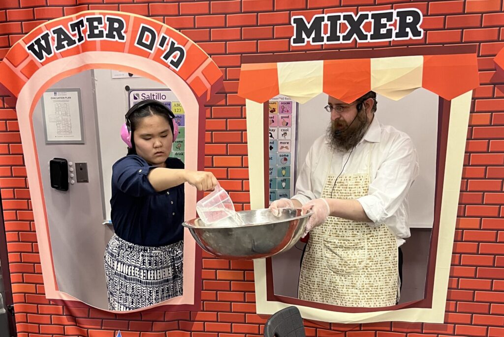 Student pouring water into matzah mix with rabbi