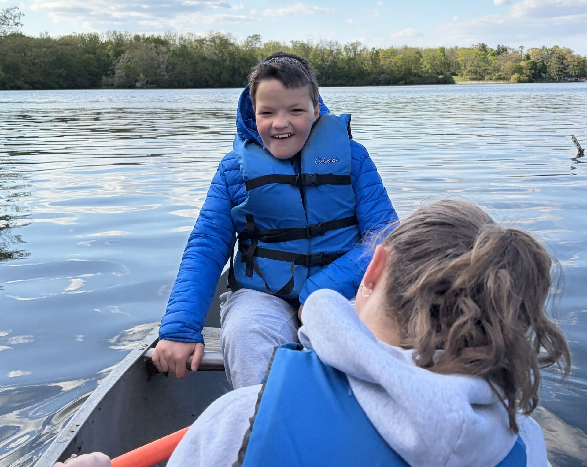 Camper smiling while sitting in a rowboat and looking at his counselor