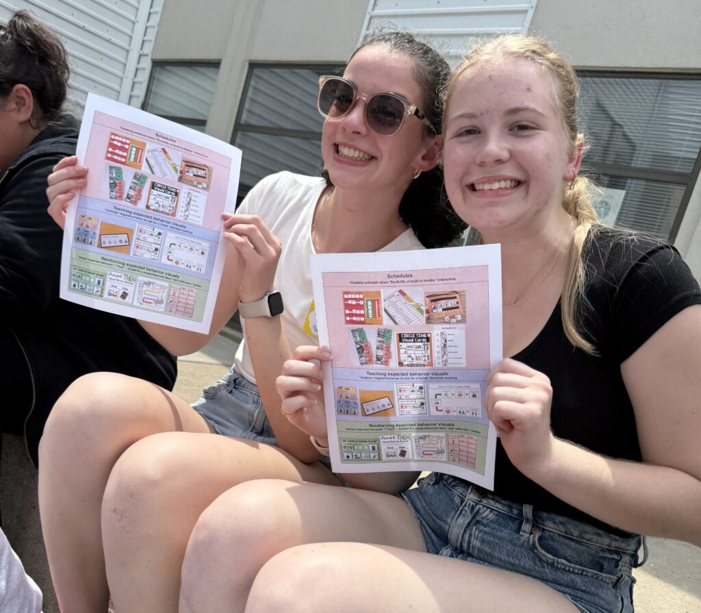 Two counselors holding up sheets of paper