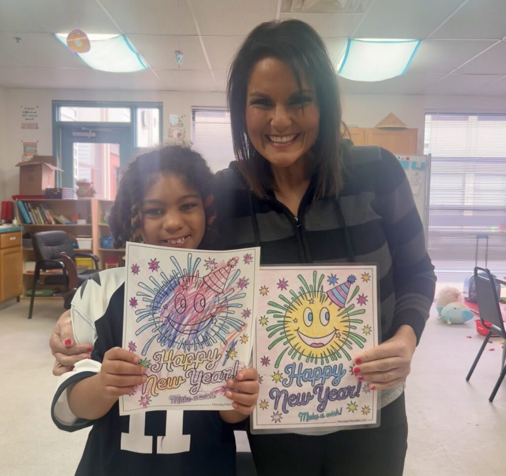 elaine smiling with a student holding up artwork