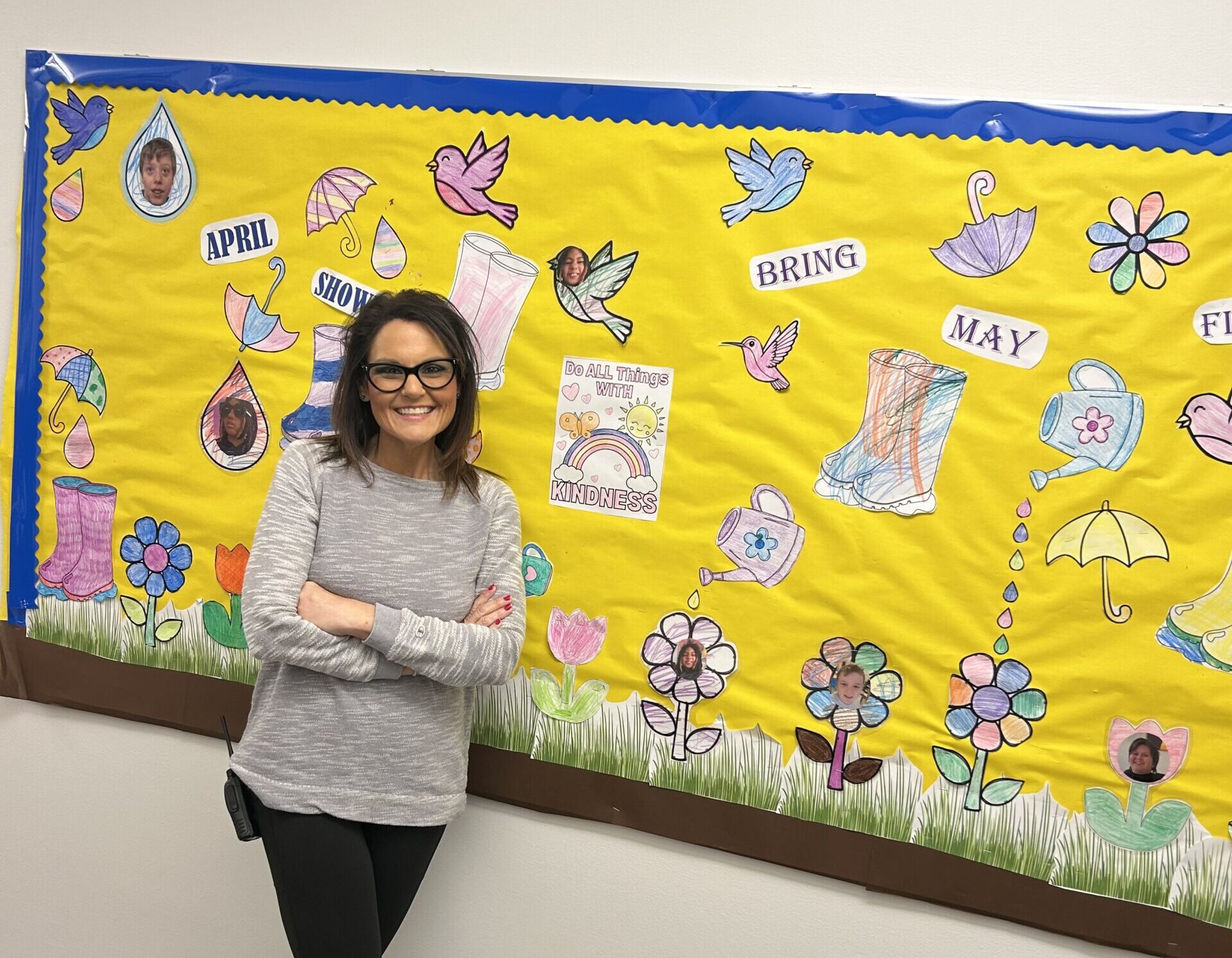 Elaine with her arms crossed smiling in front of a bulletin board
