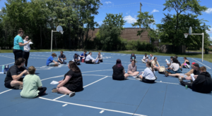 Camp staff sitting in circles on a basketball court