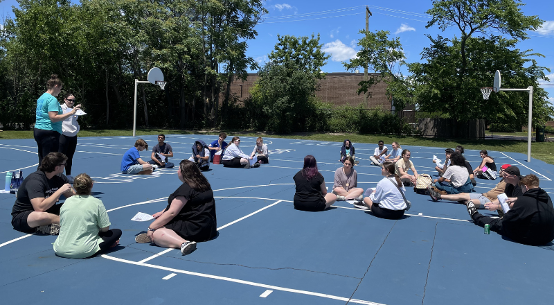 Camp staff sitting in circles on a basketball court