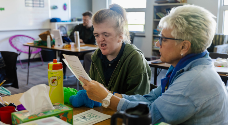 Emerson reading with a paraprofessional at a desk