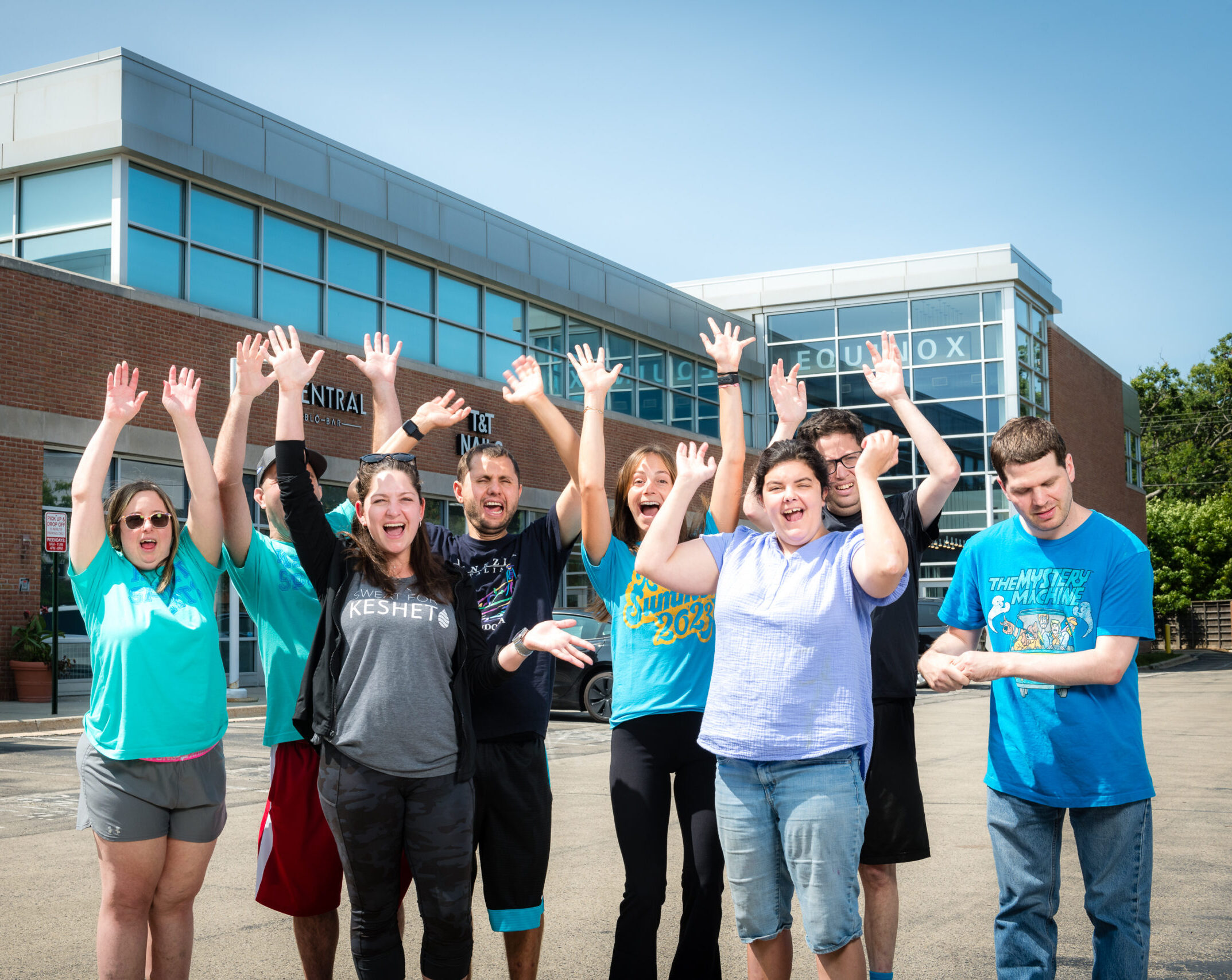 Adults with their hands up in front of the building