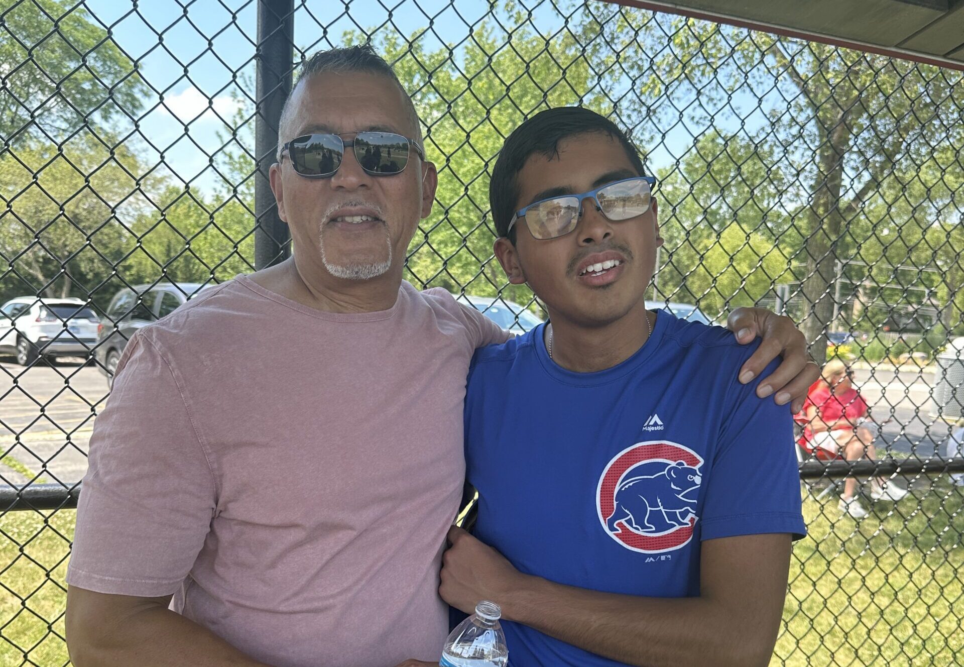 Parent and son standing together at a baseball game
