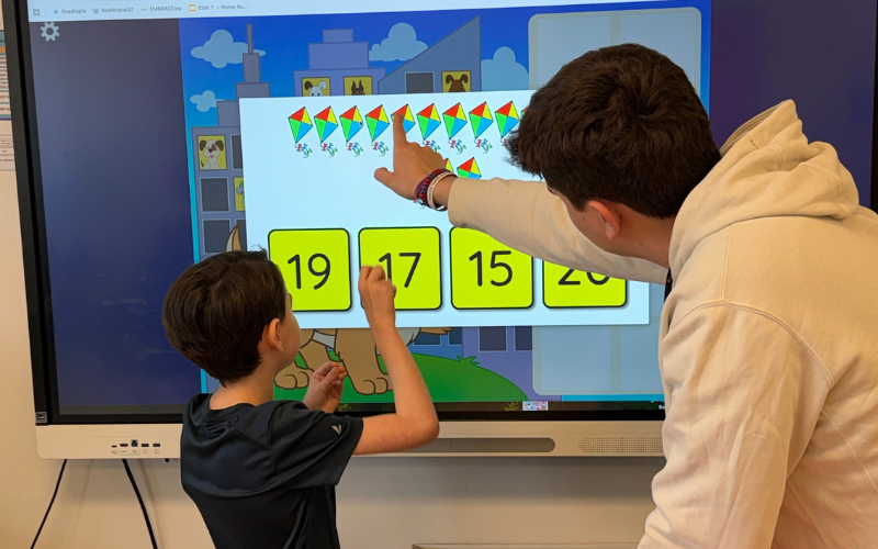 student and staff touching a smartboard