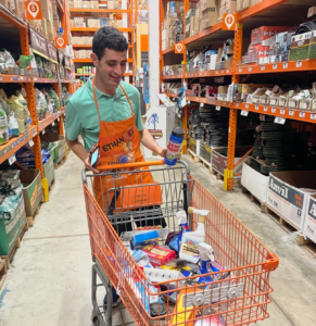 Adult pushing a cart filled with items down an aisle at home depot